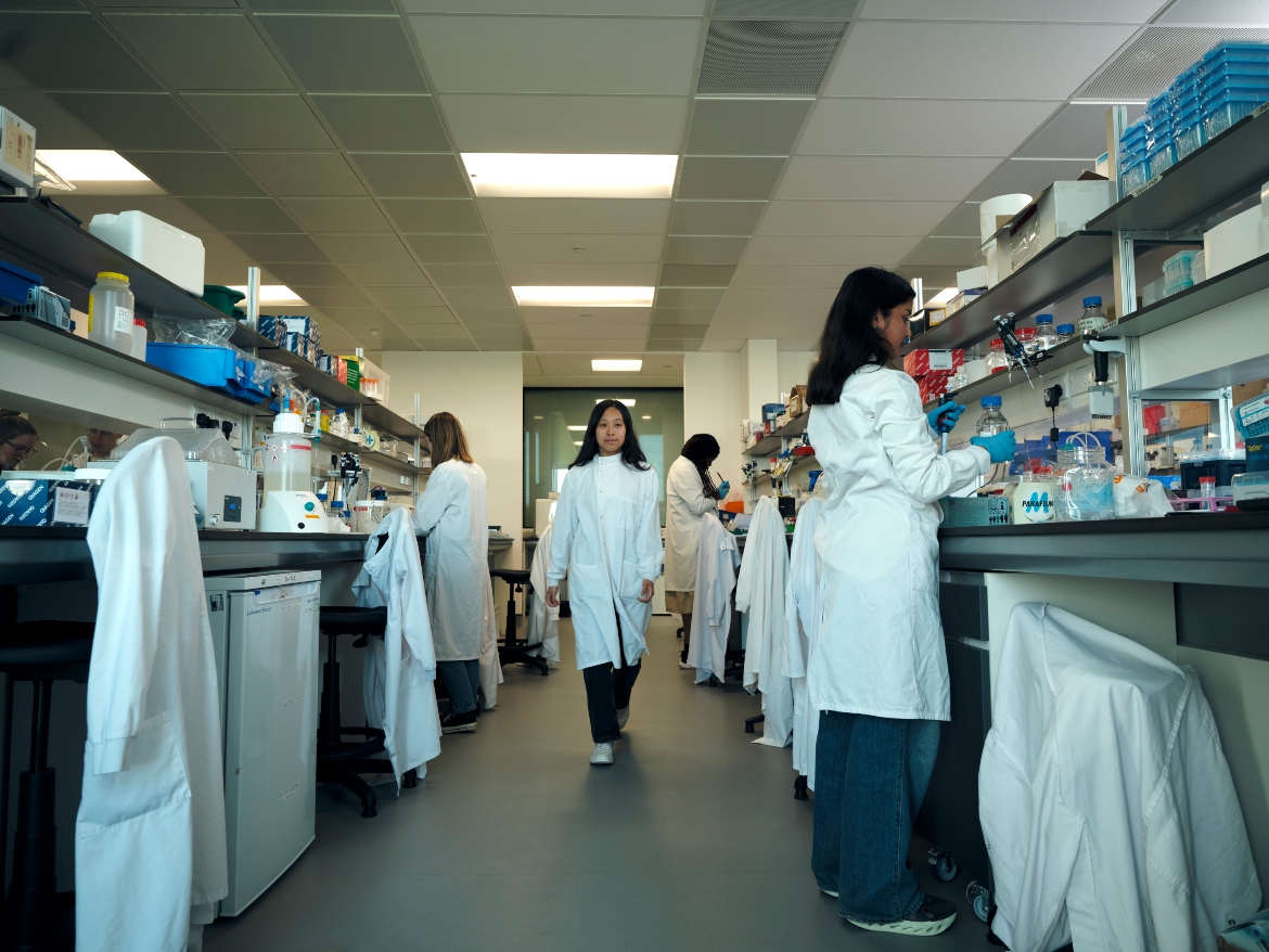 Scientist walking in a lab wearing white coat.